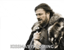 a man in a fur coat is holding a microphone and says kissmas is coming ..