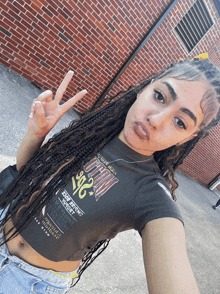 a woman wearing a crop top that says chicago giving a peace sign