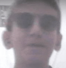 a blurry picture of a man wearing sunglasses and a black shirt .