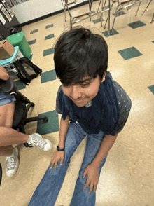 a boy sitting on the floor with his legs crossed and his head down