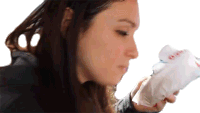 a woman is blowing her nose into a tissue while holding a bag of food