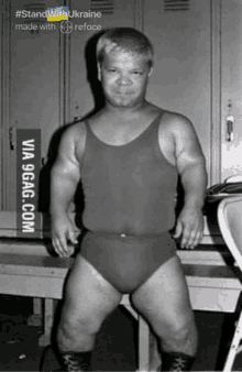 a man in a tank top and underwear is standing in front of lockers .