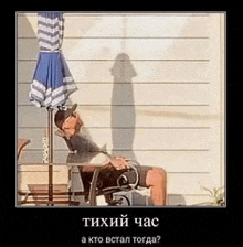 a man is sitting in a chair under an umbrella with his shadow .