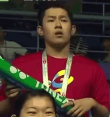 a young man wearing a red shirt and a medal around his neck is standing next to a girl .