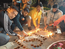 a group of men lighting candles in a circle on the ground