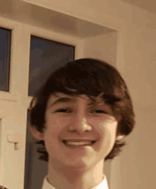 a young boy with brown hair is smiling for the camera .