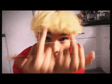 a man with yellow hair is making a middle finger gesture .