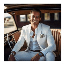 a man in a white suit is sitting in a car and smiling .