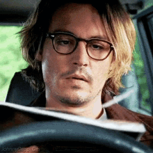 a man wearing glasses is driving a car and looking at something