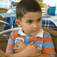 a young boy wearing a blue and orange shirt with the number 58 on it