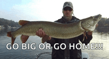 a man is holding a large fish with the words go big or go home below him