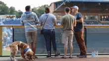 a group of people looking over a railing at a baseball game with a sign that says ' stadium ' on it