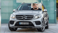 a man is sitting in a mercedes benz suv with a picture of him on the windshield .