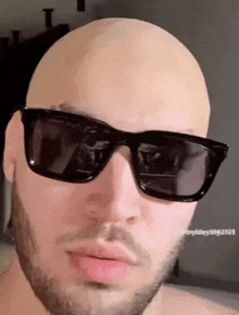 a bald man with a beard is wearing sunglasses and a wig .