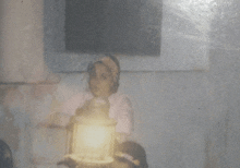 a blurry photo of a woman holding a lantern that says ' a ' on it