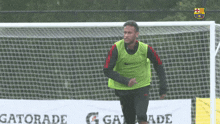 a man in a green vest is running on a soccer field in front of a sign that says gatorade