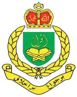 a green and yellow emblem with arabic writing and a crown on top