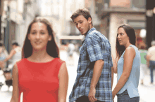 a man in a plaid shirt is walking down the street while a woman in a red dress looks on