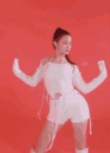 a woman in a white outfit is dancing in front of a red background