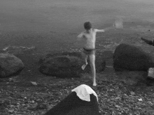 a black and white photo of a young boy jumping into a body of water