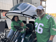 a man wearing a number 26 jersey stands next to a woman and child