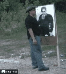 a man in a cowboy hat stands in front of a target with a picture of a man pointing a gun