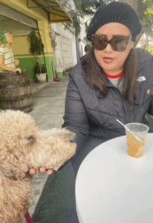 a woman in a north face jacket sits at a table with a dog