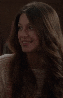 a woman with long brown hair is smiling and looking to the side