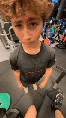 a young boy in a gym wearing a shirt that says ' apexusa ' on it