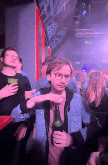 a man holding a bottle of beer in a crowded room