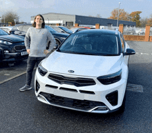 a man stands in front of a kia car