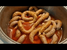 a close up of a pot filled with sausages in a sauce .