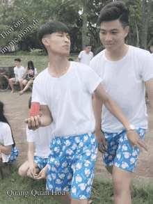 a group of young men wearing white shirts and blue shorts with quang quan hoa written on the bottom right