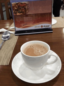 a cup of coffee sits on a saucer next to a menu on a table