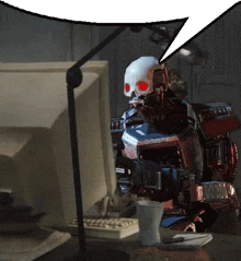 a robot with a skull and red eyes is sitting in front of a computer