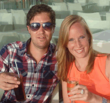 a man and a woman are posing for a picture while holding glasses of wine