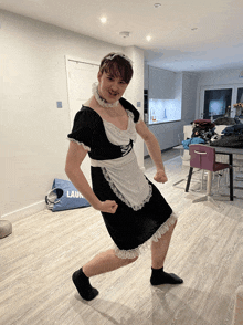 a man in a maid costume is standing in a room with a laundry bag on the floor