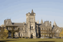 a large stone building with cars parked in front of it on a sunny day