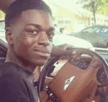 a young man is sitting in the driver 's seat of a bentley .