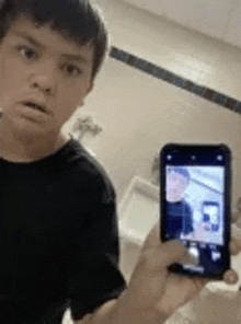 a boy is taking a picture of himself with a cell phone in a bathroom .