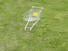 a shopping cart is sitting in the grass and has a yellow label on it