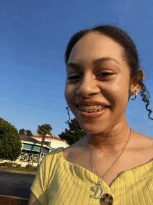 a girl with braces on her teeth wears a yellow shirt