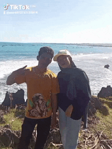 a man and a woman are posing for a picture on a rocky cliff near the ocean with tik tok written on the bottom