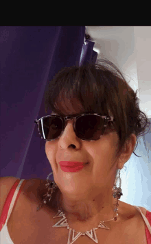 a woman wearing sunglasses and a necklace with the letter w on it