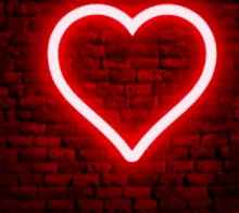 a red heart is lit up against a brick wall