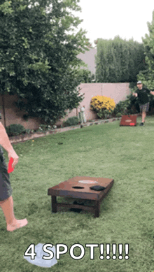 two men are playing a game of cornhole in a backyard and one of them is holding a frisbee .