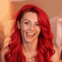 a woman with red hair is smiling and making a face .