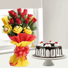 a bouquet of red roses sits next to a cake on a cake stand