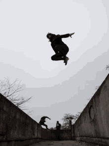 a man in a black jacket is jumping in the air while another man watches