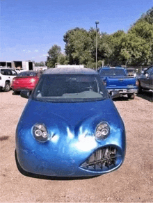 a blue car with a face painted on it is parked in a parking lot .